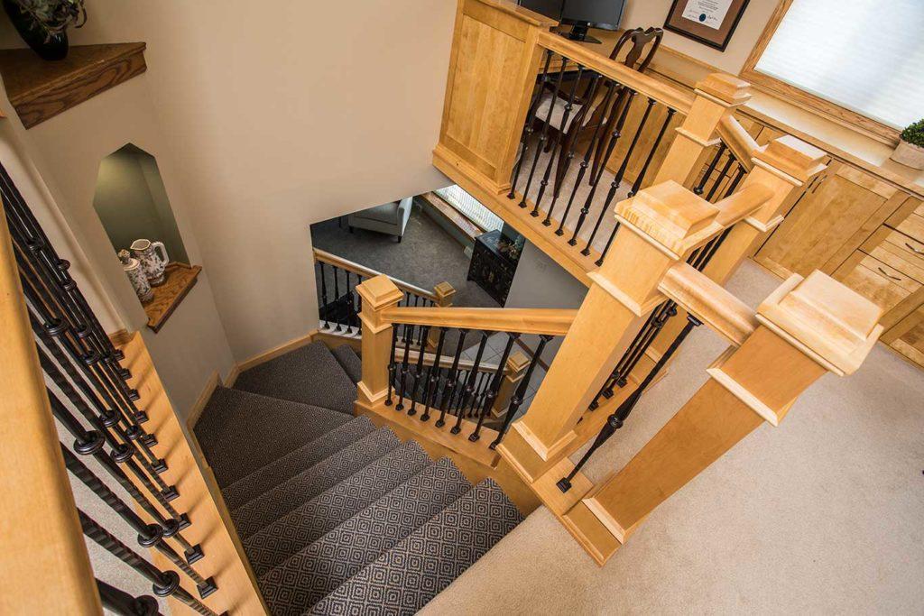 All wood stair parts replaced with a lighter and brighter stain contrasted by single and double knuckle metal balusters.